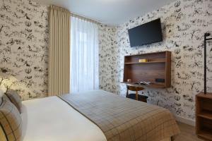 グルノーブルにあるMaison Barbillon Grenobleのベッド1台、壁掛けテレビが備わるホテルルームです。
