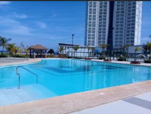 a large blue swimming pool with a tall building at Grand Condo-Hotel with Breathtaking Seaside Views in Lapu-Lapu, Cebu in Mactan