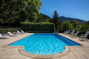 a swimming pool with lounge chairs at Hotel Les Mésanges in Saint-Martin-dʼUriage