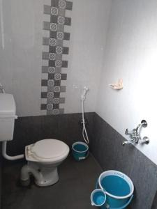 a bathroom with a toilet and two buckets on the floor at RAJE SAMBHAJI GUEST HOUSE in Belgaum