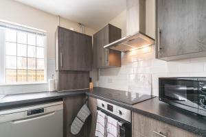 a kitchen with wooden cabinets and a black counter top at Thy Grace 3 Bedroom 2 Shower Room Central Location in Hull