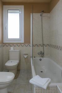 a white toilet sitting next to a bath tub in a bathroom at Hotel El Castell in Sant Boi del Llobregat