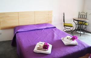 a purple bed with two towels with flowers on it at Horizon Pantelleria in Pantelleria