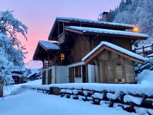 a house covered in snow with the sunset in the background at CHALET MITCH in Morzine