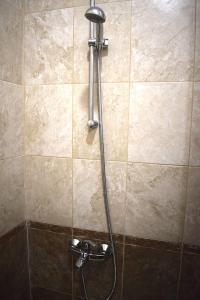 a shower with a hose on a tiled wall at Starlight Studios in Burgas City