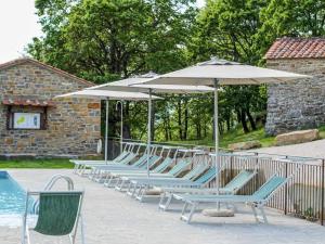 een rij stoelen en parasols naast een zwembad bij Villa Santarsa con piscina privata in Sansepolcro