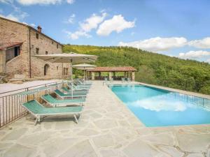 聖塞波爾克羅的住宿－Villa Santarsa con piscina privata，一座带椅子和遮阳伞的游泳池位于一座建筑旁边