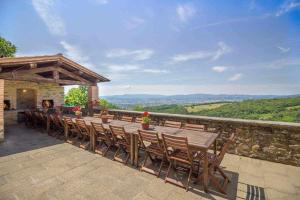une grande table et des chaises en bois sur la terrasse dans l'établissement Villa Cungi con piscina privata, à Misciano