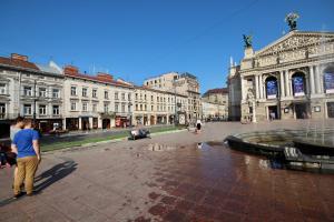 Ein Mann steht vor einem Brunnen in einer Stadt in der Unterkunft Romantic Lux Vivaldi Suite Svobode avenue 39 in Lwiw