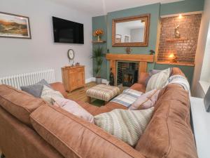 a living room with a brown couch and a fireplace at Sunshine Cottage in Buxton