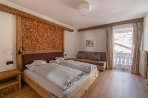 a bedroom with a bed and a couch and a window at Garni Ciasa Tamà in Corvara in Badia