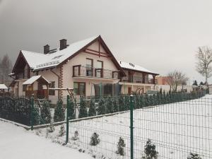 ein Haus mit Weihnachtsbäumen vor einem Zaun in der Unterkunft Pokoje Mariola in Sztutowo