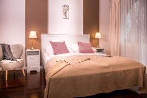 Un dormitorio con una cama con almohadas rosas y una silla en Music Apartment, en Ełk
