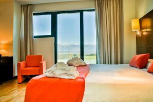 Habitación de hotel con cama y silla naranja en Hospedium Hotel Valles de Gredos Golf, en Talayuela