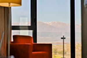 Una silla frente a una ventana con vista a la montaña. en Hospedium Hotel Valles de Gredos Golf, en Talayuela