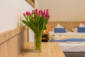 un jarrón de tulipanes rosas sobre una mesa en un dormitorio en Grand Tatry, en Białka Tatrzanska