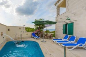 - une piscine avec des chaises bleues et un parasol dans l'établissement Villa Angelina Supetar, à Mirce