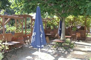 a patio with tables and chairs and a blue umbrella at Hotel Ratsstuben in Rehden