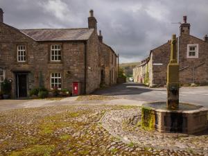 an empty street in a village with stone buildings at Winskill Cottage in Settle