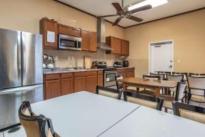 cocina con mesas, sillas y nevera en Comfort Suites Airport South, en Montgomery