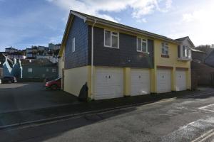 a yellow house with two white garage doors at The Mews in Dartmouth