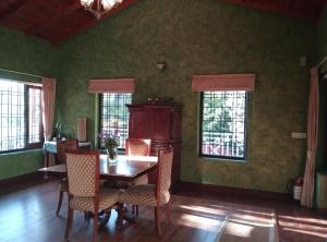 a dining room with green walls and a wooden table and chairs at Abbotsford Prasada Bhawan in Nainital