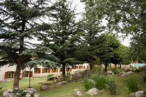un jardin avec des arbres et des rochers devant un bâtiment dans l'établissement Hotel Tafí, à Tafí del Valle
