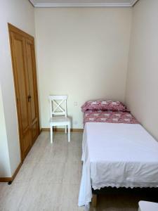 een kleine slaapkamer met een bed en een stoel bij Beautiful first line beach apartment Samil in Vigo