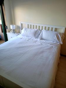 een bed met witte lakens en kussens erop bij Beautiful first line beach apartment Samil in Vigo