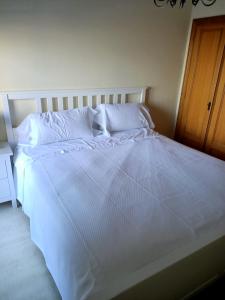 een groot wit bed met witte lakens en kussens bij Beautiful first line beach apartment Samil in Vigo