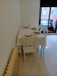 een eettafel met een witte tafel en stoelen bij Beautiful first line beach apartment Samil in Vigo