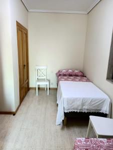 een kleine kamer met 2 bedden en een stoel bij Beautiful first line beach apartment Samil in Vigo