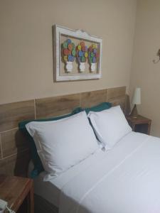 a white bed with two pillows and a picture on the wall at Pousada Casa do Bosque in Penedo