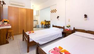 a bedroom with two beds and a dining room at Evi Apartments And Studios in Theologos