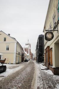 a snowy street with a clock on the side of a building at Apple Economy Hotel in Kaunas
