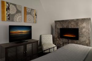 a bedroom with a bed and a tv and a fireplace at The Kalamazoo House Downtown Hotel and Suites in Kalamazoo