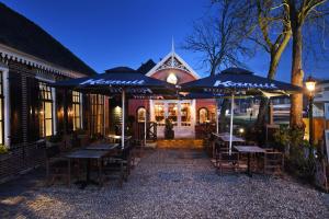 un restaurant avec des tables et des parasols en face d'un bâtiment dans l'établissement Small Luxury Boutique Hotel Wilma J, à Vinkeveen