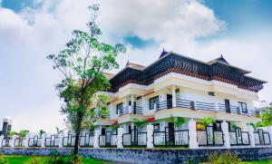 una casa blanca con una valla y un árbol en Vagamon Vagashore, en Vagamon