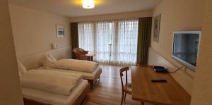 una camera d'albergo con due letti e una televisione di Hotel Breiti a Bachenbülach Altre 8 foto