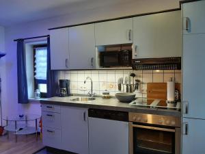 a kitchen with white cabinets and a sink at Fewo an der Teufelskanzel in Annaberg-Buchholz