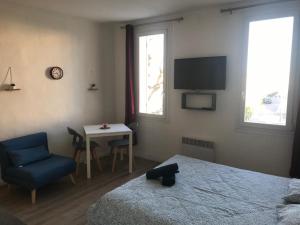 ein Schlafzimmer mit einem Bett, einem Stuhl und einem Tisch in der Unterkunft Accostage Vieux-Port - Appartements & Parking in La Ciotat