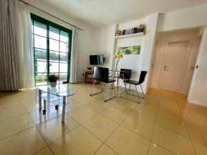 Apartamento Dorada Alto في بلايا بلانكا: غرفة معيشة مع طاولة وكراسي زجاجية