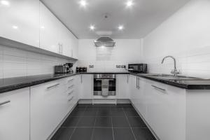 a white kitchen with white cabinets and a sink at Suites by Rehoboth - Building XXII - Royal Arsenal in Woolwich