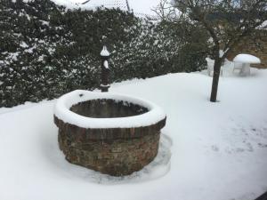a snow covered stone bowl with a pole in the snow at De Witte Molen Kranenburg in Kranenburg