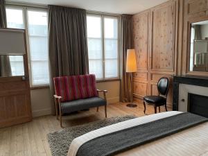 a bedroom with a bed and a chair and a fireplace at Le Jardin Découverte in Conches-en-Ouche