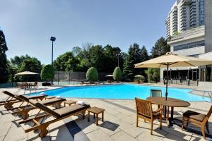 a swimming pool with tables and umbrellas next to a building at Pan Pacific Toronto in Toronto