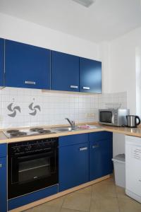a kitchen with blue cabinets and a stove top oven at Ferienwohnungen an der Therme in Bad Rodach