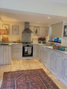 a large kitchen with gray cabinets and an oven at Jasmine Cottage in Chipping Campden