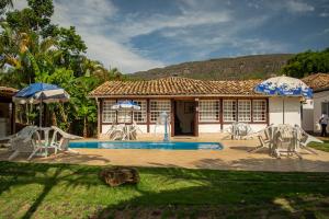 una casa con piscina con sillas y sombrillas en Pousada Chafariz das 4 Estações, en Tiradentes