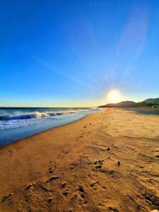 una playa de arena con el sol saliendo sobre el océano en New holiday house "Casa miAlina" with private pool, 300m to beach en Cambrils